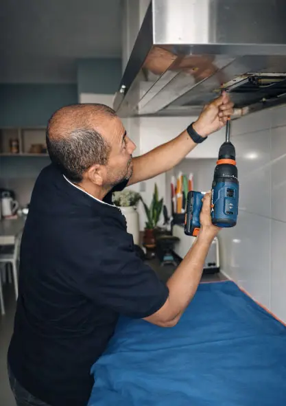 Técnico especialista reparando una campana extractora de cocina en un domicilio de Barcelona.